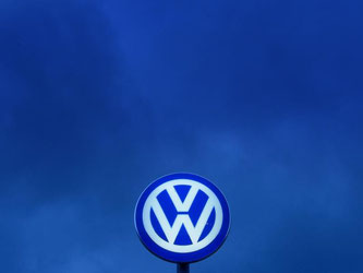 Das VW-Logo leuchtet Abendhimmel über dem Werkstor von Volkswagen in Wolfsburg. Foto: Peter Steffen/Illustration