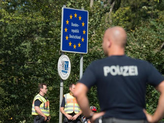 Bundespolizisten stehen an einem Grenzschild der Bundesrepublik Deutschland an der deutsch-österreichischen Grenze zwischen Salzburg und Freilassing (Bayern). Foto: Armin Weigela