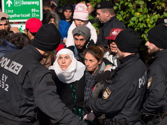 Polizisten sprechen an der deutsch-österreichischen Grenze bei Passau mit Flüchtlingen aus Syrien. Foto: Sebastian Kahnert