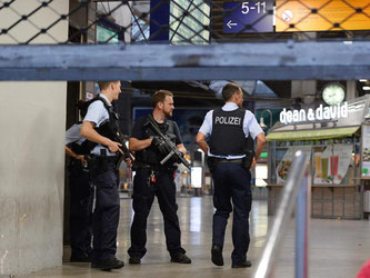 Polizisten mit Maschinenpistolen stehen in München am Hauptbahnhof und sichern das Gelände. Foto: Andreas Gebert