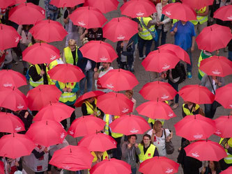 Demonstranten mit roten Regenschirmen in Hamburg während einer Aktion der Gewerkschaft Verdi unter dem Motto «Tarifverträge schützen». Foto: Daniel Reinhardt