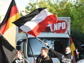 Teilnehmer an einer Kundgebung der NPD winken in Berlin mit ihren Fahnen. Foto: Jens Kalaene