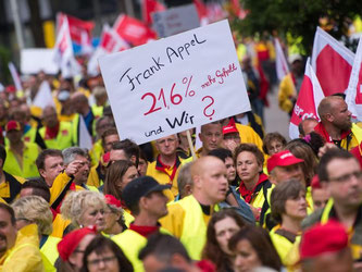 Ein Postler fragt auf seinem Plakat: "Frank Appel - 21,6% mehr Gehalt und Wir?". Mehrere tausend Beschäftigte der Post demonstrierten vor der Konzernzentrale. Foto: Marius Becker