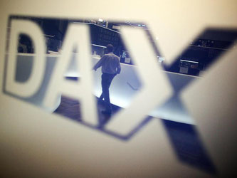In der Börse in Frankfurt am Main spiegelt sich ein Händler in einem Logo des Deutschen Aktienindex (DAX). Foto: Fredrik von Erichsen