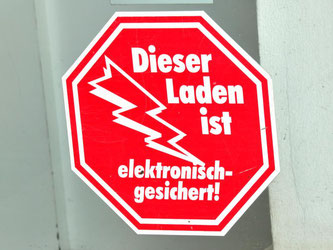 Ein Aufkleber «Dieser Laden ist elektronisch gesichert!». Foto: M. Schutt/Archiv