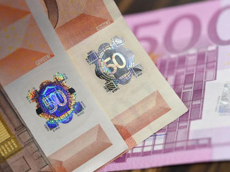 Die Hologramme einer echten 50-Euro-Note (l) und einer falschen in der Zentrale der Deutschen Bundesbank in Frankfurt neben einer gefälschten 500-Euro-Note. Foto: Arne Dedert