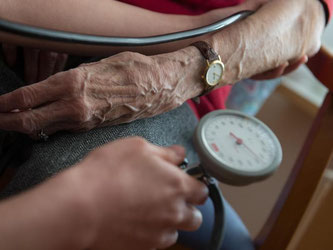 Eine Bewohnerin einer Seniorenwohnanlage bekommt den Blutdruck gemessen. Foto: Marijan Murat/Illustration