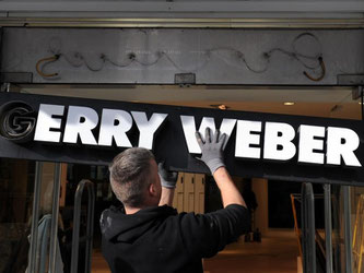 Das Schild mit dem Schriftzug "Gerry Weber" wird am Kurfürstendamm in Berlin an der kürzlich geschlossenen Filiale der Modemarke abmontiert. Foto: Violetta Kuhn