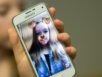 Auf dem Smartphone einer Teenagerin ist die geöffnete Snapchat-App zu sehen. Foto: Patrick Seeger/Illustration