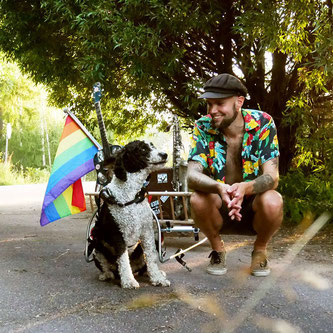 Martin mit einem Hund und Regenbogenfahne vor einem Baum.