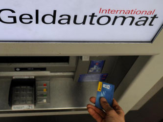 Ein Bankkunde hebt mit seiner Girokarte Bargeld von einem Geldautomaten ab. Foto: Angelika Warmuth/Illustration
