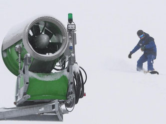 Ein Snowboardfahrer fährt auf dem Feldberg an einer Schneekanone vorbei. Foto: Patrick Seeger/Archiv