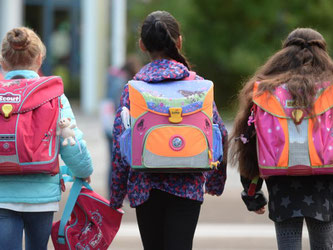 Drei Schülerinnen laufen mit ihren Schulranzen zur Schule. Foto: Patrick Seeger/Archiv