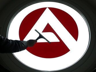 Ein Fenster mit dem Logo der Bundesagentur für Arbeit wird gereinigt. Foto: Roland Weihrauch/Illustration
