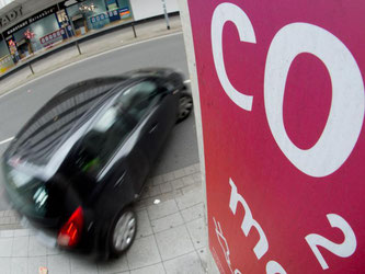 Ein Auto fährt an einem Schild mit Aufschrift «CO2» (Kohlendioxid) vorbei. Foto: Julian Stratenschulte/Illustration