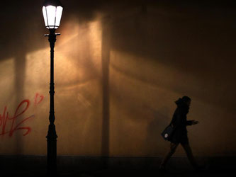 Eine Frau geht im Licht einer Straßenlaterne spazieren. Foto: Karl-Josef Hildenbrand