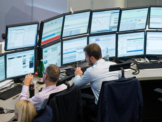 Börsenhändler betrachten die Bildschirme im Handelssaal der Frankfurter Börse - ihre Einschätzung verursacht für den Anleger Kosten. Foto: Frank Rumpenhorst