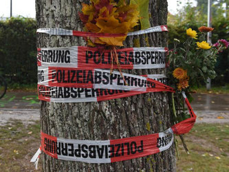 Blumen sind mit einem Absperrband der Polizei an einem Baum in Freiburg befestigt. Foto: Patrick Seeger/Archiv