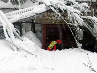 Ein Retter verschafft sich Zugang zu dem von einer Lawine verschütteten Hotel "Rigopiano" bei Farindola in den Abruzzen. Foto: The National Alpine Cliff and Cave Rescue Corps