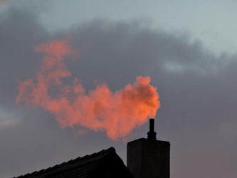 Der Rauch eines Schornsteins leuchtet rot. Angesichts niedriger Brennstoffpreise legen sich wieder mehr Hausbesitzer eine Ölheizung zu. Foto: Daniel Karmann/Archiv