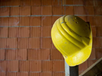 Ein Bauhelm hängt auf einer Baustelle. Foto: Daniel Bockwoldt/Archiv