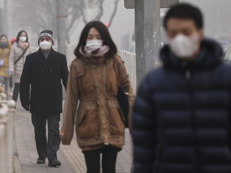 Passanten gehen mit Atemschutz-Masken durch dichten Smog in Peking. Foto: Rolex Dela Pena/Archiv
