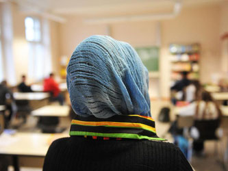 Eine Schülerin mit Kopftuch nimmt am Unterricht in einer Schule teil. Foto: Bernd Thissen/Illustration