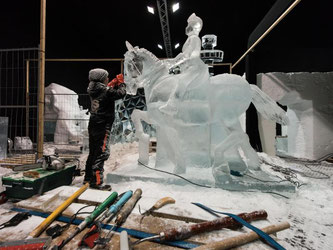 Dick eingepackt arbeitet eine Eiskünstlerin an einer Reiterskulptur aus Eis. Foto: Patrick Seeger