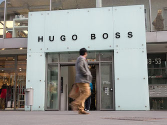 Ein Mann geht am Eingang des Hugo Boss-Fabrikverkaufs in Metzingen vorbei. Foto: Sebastian Kahnert/Archiv