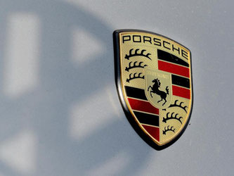 Der Schatten eines VW-Logos fällt auf das Logo von Porsche. Foto: Franziska Kraufmann/Archiv