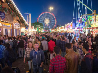 Besucher des Cannstatter Volksfestes laufen über die Wasen. Foto: Deniz Calagan/Archiv