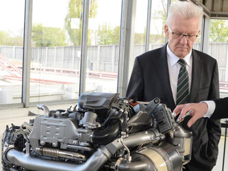 Winfried Kretschmann betrachtet einen Dieselmotor. Foto: Franziska Kraufmann/Archiv