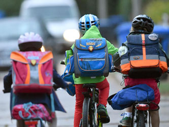 Drei Schulkinder fahren mit dem Fahrrad zur Schule. Foto: Ralf Hirschberger/Archiv