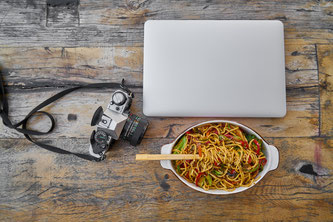 Fotokamera Laptop und Nudeln auf einem Tisch