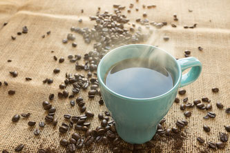 Tasse Kaffee neben Kaffeebohnen