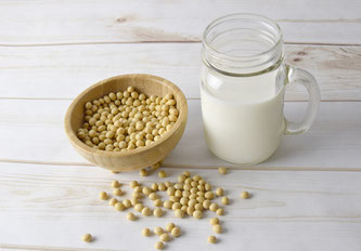 Eine Kanne Milch neben Sojabohnen