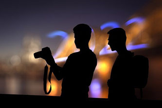 Silhouette von 2 Männern mit Fotoapparat vor der erleuchteten Zahl 2022