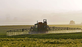 fahrender Traktor bei der Pestizidanwendung in einem Feld