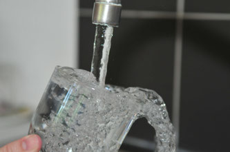 Wasser läuft aus Wasserhahn in Glas