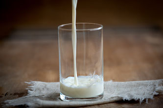 Milch wird in ein Glas eingeschenkt