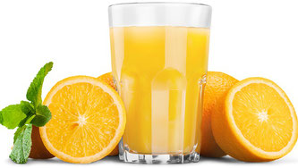 Ein Glas Orangensaft neben halbierten Orangen