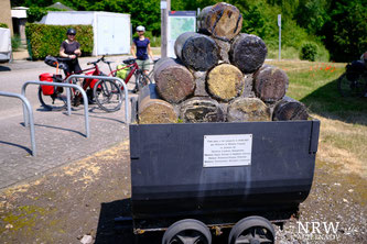 Eine alte Lore, im Hintergrund zwei Radfahrerinnen. 