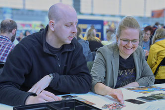 Zwei Menschen sitzen an einem Tisch und spielen ein Gesellschaftsspiel