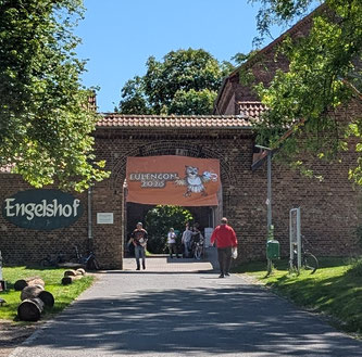 Ein offenes Tor mit zwei Schildern und Menschen, die herumgehen.