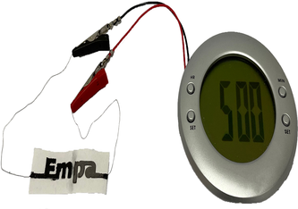 Eine mit Hilfe einer Schablone gedruckte Papierbatterie in Form des Namens unseres Forschungsinstituts («Empa»): Die Batterie kann elektronische Geräte mit geringem Stromverbrauch betreiben, beispielsweise einen Wecker mit LCD-Anzeige, der an die Bat