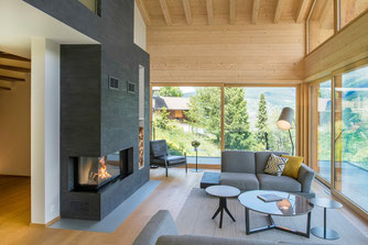 moderner Ofen aus Stein. Modernes Wohnzimmer mit Holz und grossen Fenstern