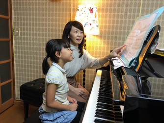 水戸市のまりピアノ教室の先生が生徒さんに楽譜を指しながらレッスンしている様子