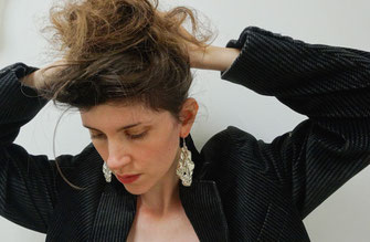 Une femme porte deux grosses boucles d'oreilles en argent.