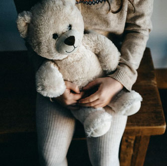 Teddybär im Arm eines Kindes