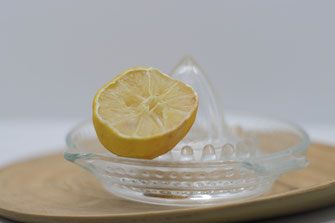 Zeste de citron sur un presse citron en verre sur un plateau en bambou sous fond blanc